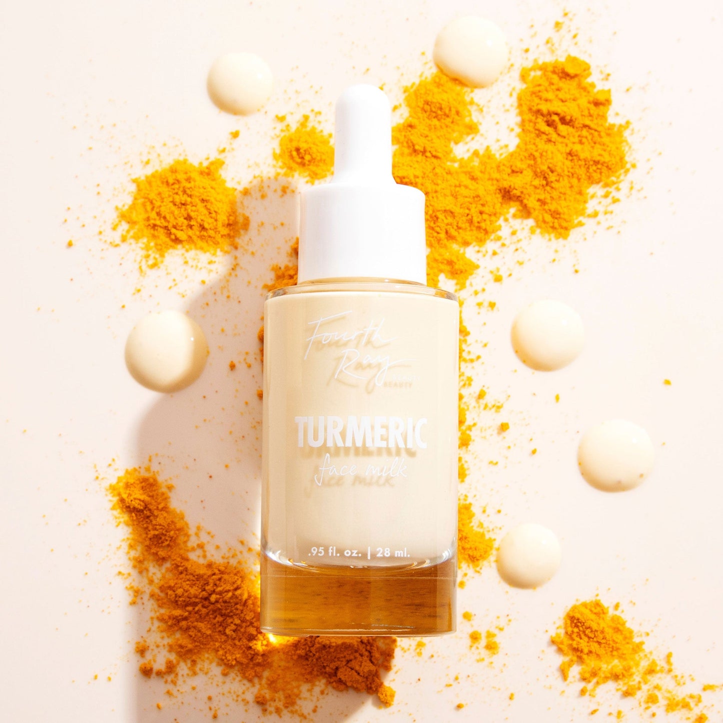 Fourth Ray Beauty Turmeric Face Milk dropper bottle with white cap stands upright, 0.95 fl oz/28 mL, filled with pale yellow serum, surrounded by creamy droplets and bright orange turmeric powder on a light backdrop, featuring ColourPop Face Milk skincare.
