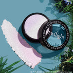Meadow Super Shock Highlighter catches the light in an open compact, revealing an icy lavender, iridescent sheen with a pearly swatch beside it on a teal surface framed by greenery - ColourPop Super Shock Highlighter for a radiant glow.